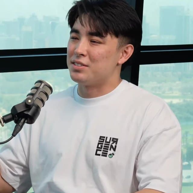Julian Stafford speaking at a podcast microphone in a Surgence Labs t-shirt